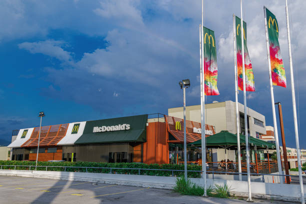 Thessaloniki, Greece - June 25 2019: McDonalds store facade new design. External day view of international fast-food chain with famous yellow arch company logo and waving flags. stock photo