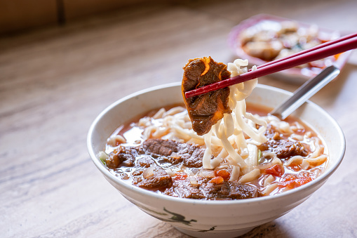 Fideos de ternera - Comida ramen de Taiwán con caldo de salsa de tomate en tazón en la mesa de madera brillante, comida de estilo chino famoso, de cerca, vista superior, espacio de copia photo