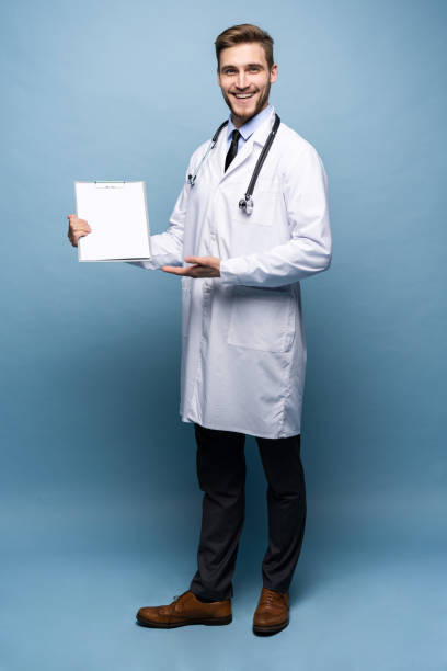 istock Male Doctor standing with folder, Doc is wearing white uniform and a tie, stands on a light blue background. 1161338875
