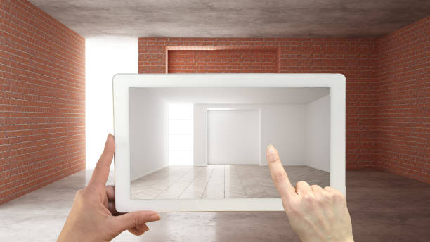 istock Augmented reality concept. Hand holding tablet with AR application used to simulate furniture and design products in an interior construction site, empty interior with parquet floor 1161341154