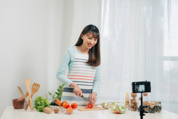 istock Online cooking classes. Food blogging. Woman preparing meal and shooting video tutorial on camera. 1161342517