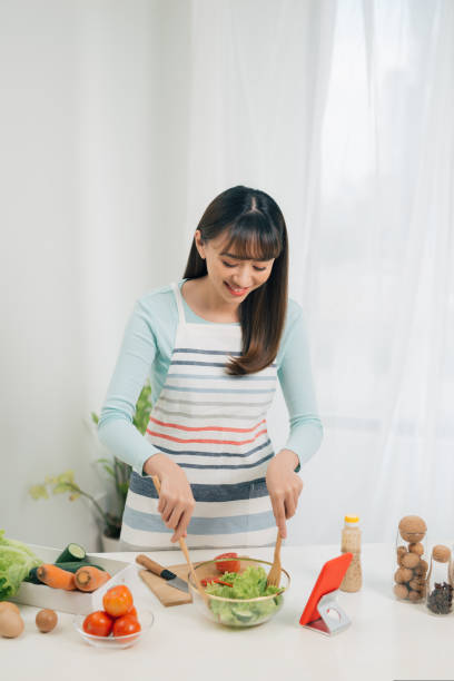istock Cooking woman looking at mobile while preparing food in kitchen 1161342749