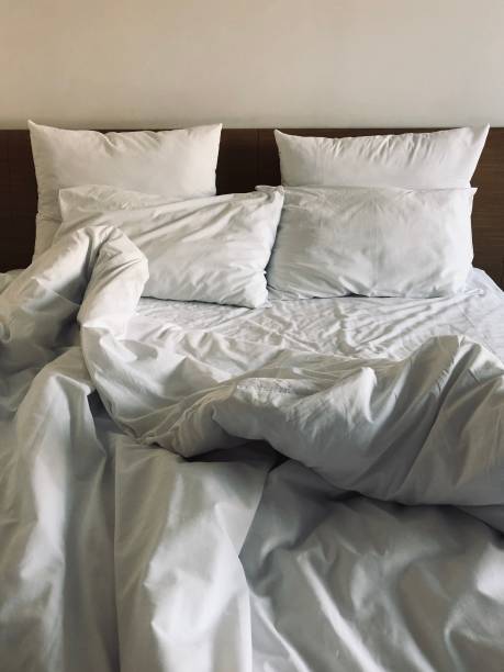 istock A messy bed with comforter and pillows - stock photo 1161344686