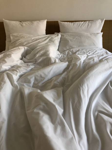istock A messy bed with comforter and pillows - stock photo 1161344689