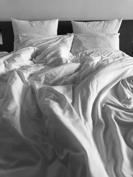 istock A messy bed with comforter and pillows - stock photo 1161344709
