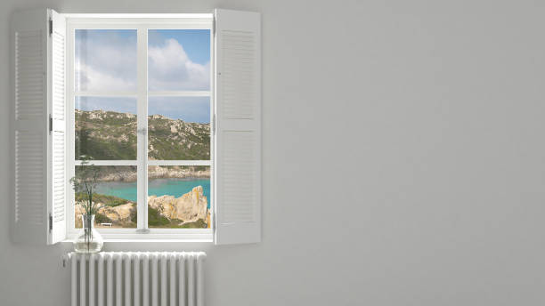 istock Stylish empty room with panoramic window close-up, classic shutters, glass vase with flowers. Sea landscape, granite rocks. White background with copy space, interior design concept 1161344941