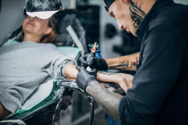 istock Tattoo artist tattooing a woman's arm 1161346838