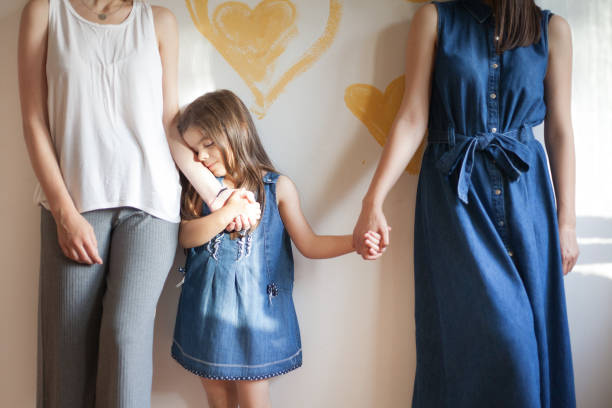 Lesbian couple posing in front of the wall with their adorable little daughter