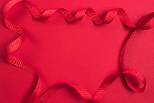 istock Ribbon`s frame. A delicate red wavy ribbon on a red background. Image for your text. 1161347996
