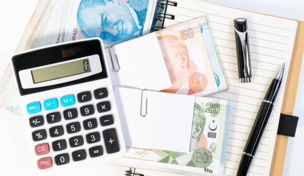 calculator, pen, notebook and one hundred banknote turkish lira currency stacked up on white background for business, finance and exchange. - tl imagens e fotografias de stock