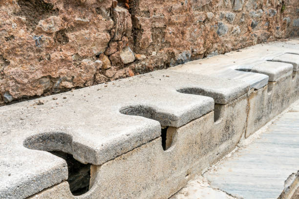 public multi seat toilet marble stone and rock at spectacular antique ruins in ephesus at selcuk izmir, turkey. - toilet public restroom ephesus history imagens e fotografias de stock