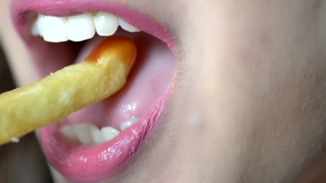 scene-slow-motion-of-extreme-close-up-of-young-woman-eating-french-fries-concept-of-healthy.jpg