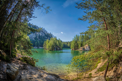 panoramic view of a small lake between rocks and trees