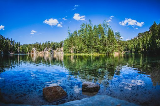 panoramic view of a small lake between rocks and trees