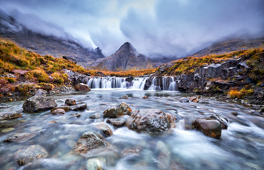 Waterfall in the Fairy Pools, Glen Brittle, Isle of Skye, Scotland, UK. On a gray day in the fall you see the water flowing along the rocks with in the background the famous mountain with the crack in the middle from top to bottom