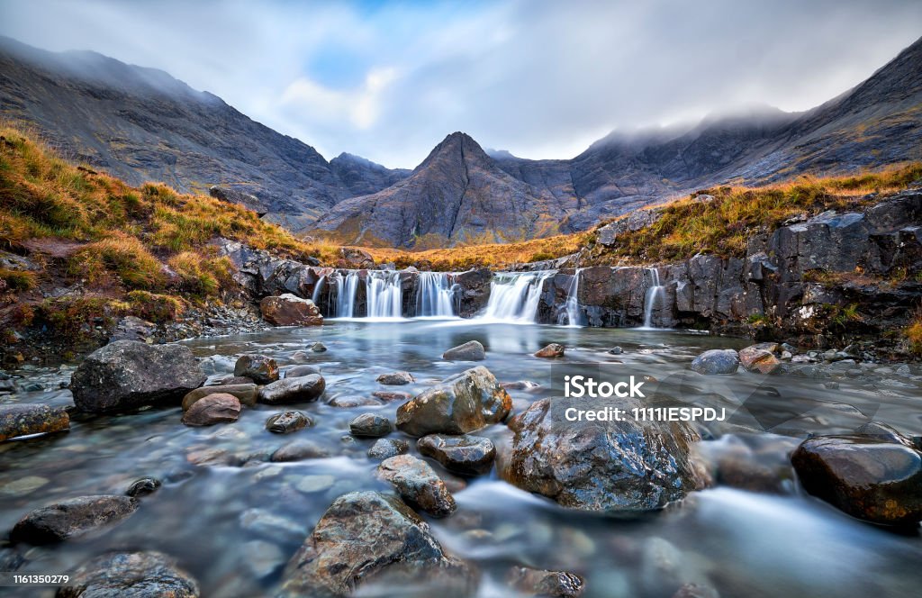 Fairy Pools, Glen Brittle, Isle of Skye, Scotland, UK Waterfall in the Fairy Pools, Glen Brittle, Isle of Skye, Scotland, UK. On a gray day in the fall you see the water flowing along the rocks with in the background the famous mountain with the crack in the middle from top to bottom Landscape - Scenery Stock Photo