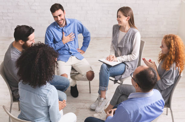 Cheerful man appreciates support of people at rehab group meeting Cheerful man appreciates support of people at rehab group meeting, empty space alcoholics anonymous photos stock pictures, royalty-free photos & images