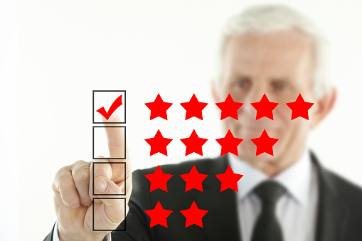 Senior businessman using touch screen to give five star review.