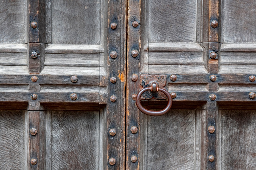 Close up image of a rusty, old-fashioned door knob on an ancient, Gothic-style doorway.