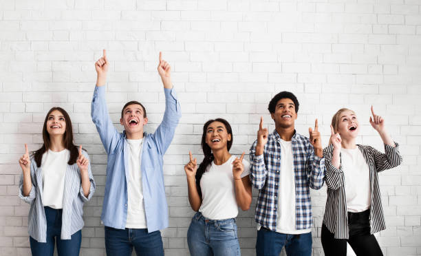 istock Teens pointing up on free space over white brick wall 1161353083