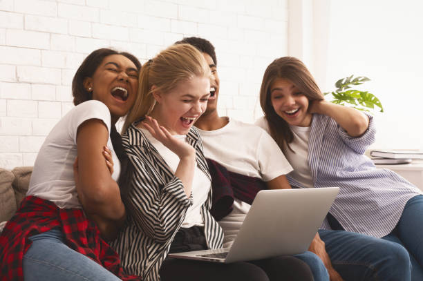 Laughing friends watching funny video on laptop