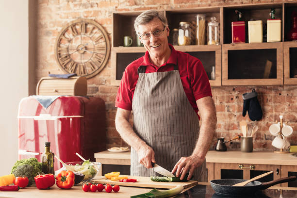 istock Handsome senior man cooking healthy vegetable salad at kitchen 1161353453