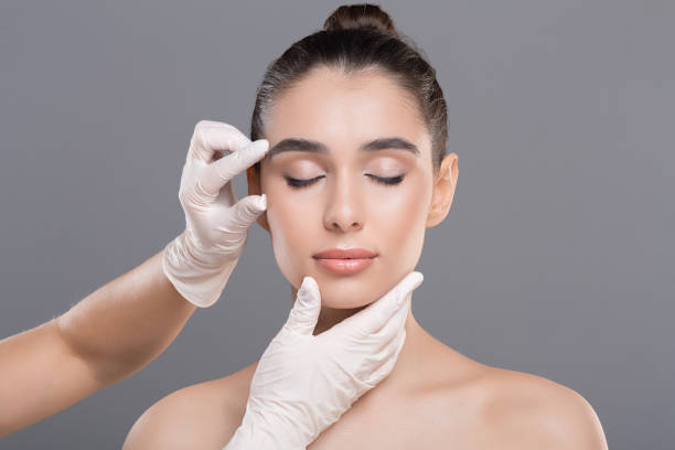 cosmetologist examining facial wrinkles on young woman face - nose job imagens e fotografias de stock