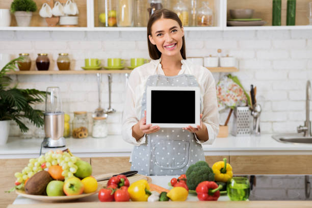 istock Woman holding tablet with blank screen, cooking dinner 1161353701