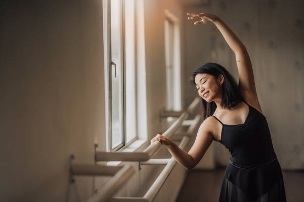 une danseuse chinoise asiatique de ballet pratiquant dans le studio de ballet près de la taille de fenêtre vers le haut - fitness dance photos et images de collection