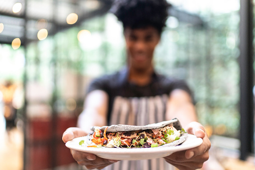 Waiter showing plate with a vegetarian wrap