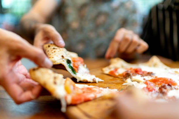 amici che si affettano la pizza, usano le mani - pizza cheese portion mozzarella foto e immagini stock