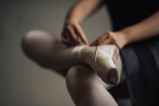 una joven bailarina de ballet asiática china preparándose para atesuado de su cordón de zapatos antes de practicar su baile de ballet en el estudio de ballet - ballet shoe dancing ballet dancer fotografías e imágenes de stock