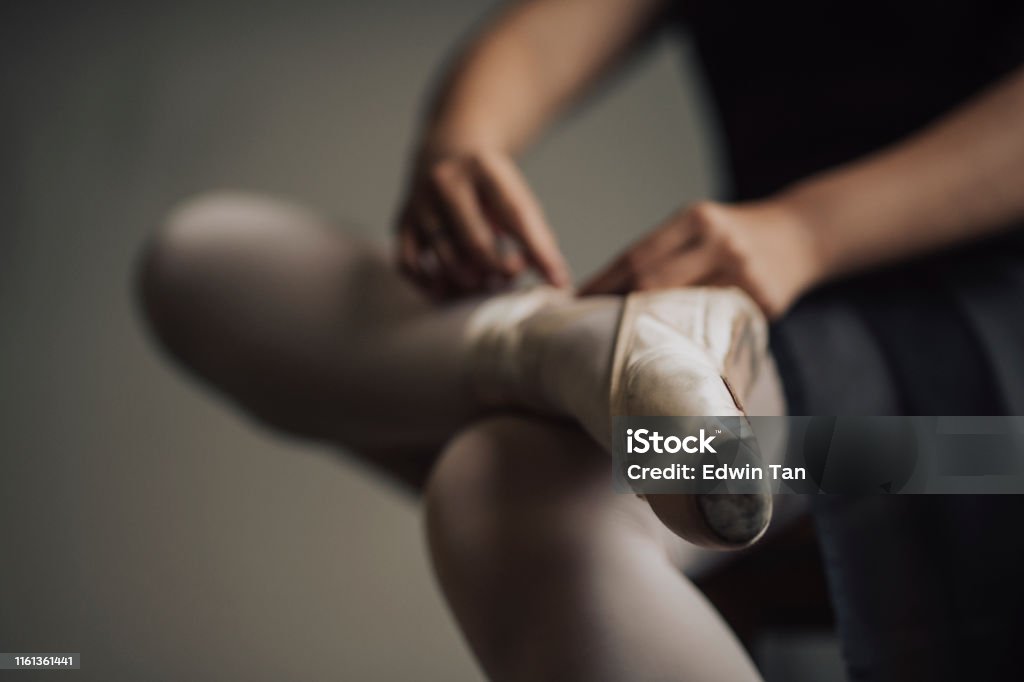 a young asian chinese female ballet dancer getting ready tying her shoelace before practising her ballet dance in ballet studio Ballet Stock Photo