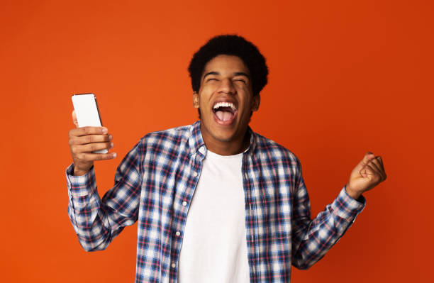 istock African Guy Holding Smartphone and Celebrating Success 1161364130