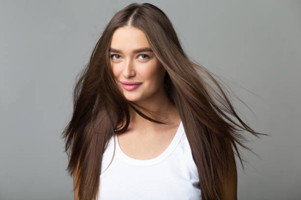 長いフライングヘア、灰色の背景を持つ若い女の子 - women smiling beautiful brown hair ストックフォトと画像