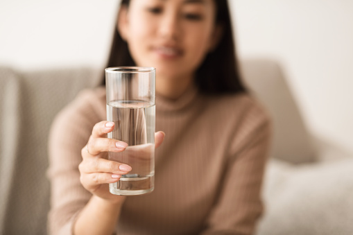 Asiática chica sosteniendo agua mineral en vidrio photo