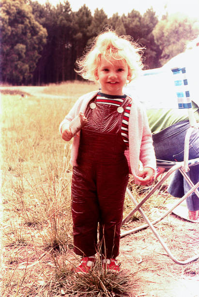Vintage photo of a cute blonde girl in nature, standing in front of the camera eating ice cream.