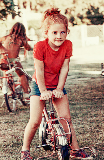Vintage photo of a cute blonde girl on her little bike