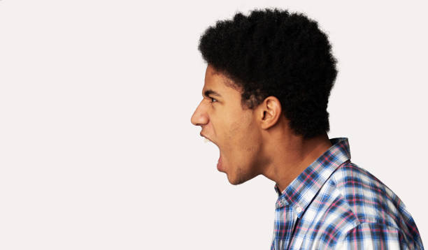 guy afro furieux criant au-dessus du fond léger - screaming fear teenager shouting photos et images de collection