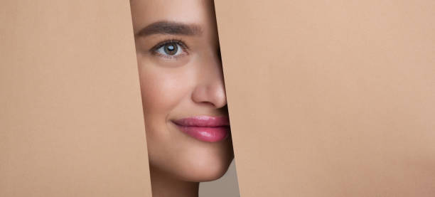 istock Woman Peeking Out From Hole In Peach Paper 1161365507