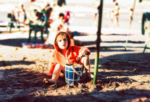 Vintage photo of a cute blonde kid playing at the beach.