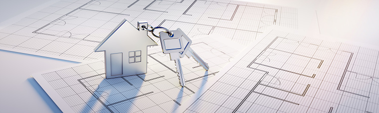 Silver Keychain with house symbol and two keys on a floor plan drawing in sunlight