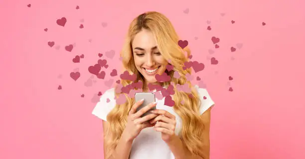Photo of Happy woman holding mobile phone with many hearts