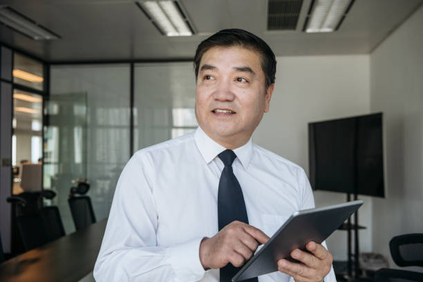 istock Mature Chinese business executive standing with digital tablet 1161376283