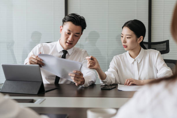 istock Young Chinese executives examining document in meeting room 1161376286