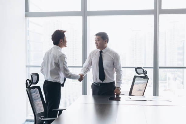 istock Young Chinese businessman shaking hands with smiling CEO 1161376314