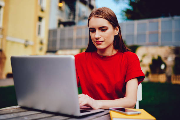 istock Attractive carefree hipster girl watching webinar online on laptop computer while sitting at street cafe, young caucasian woman downloading file from web page on contemporary netbook outdoors 1161381576
