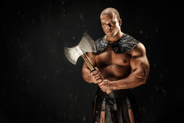 Severe barbarian in leather costume with axe. Studio shot. Black background.