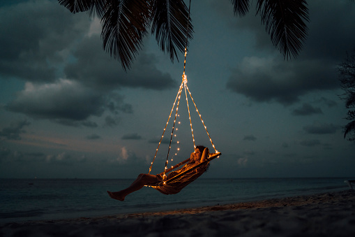 Young adult woman relaxing on a swing in a tropical paradise