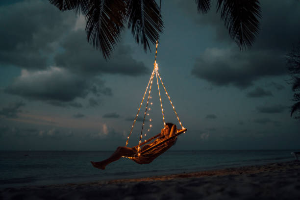 Young adult woman relaxing on a swing in a tropical paradise Young adult woman relaxing on a swing in a tropical paradise glamping photos stock pictures, royalty-free photos & images